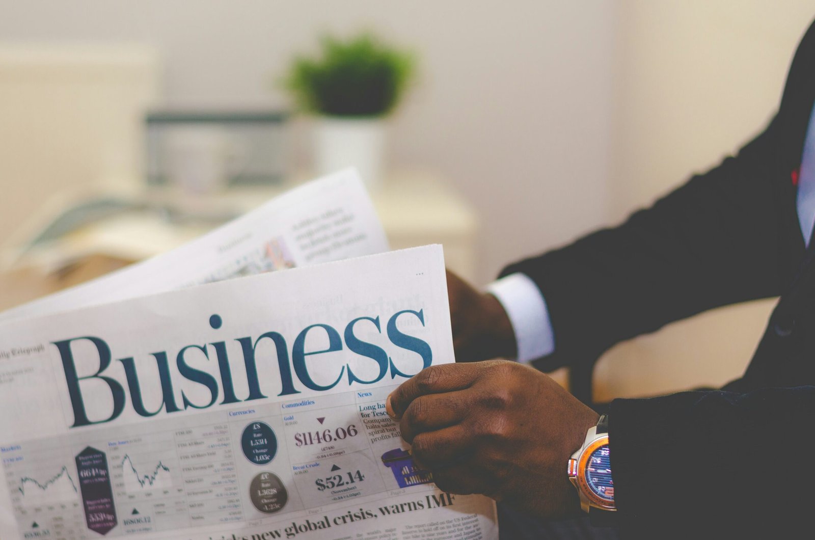 A reader in a suit reviewing business headlines and market figures in the morning paper